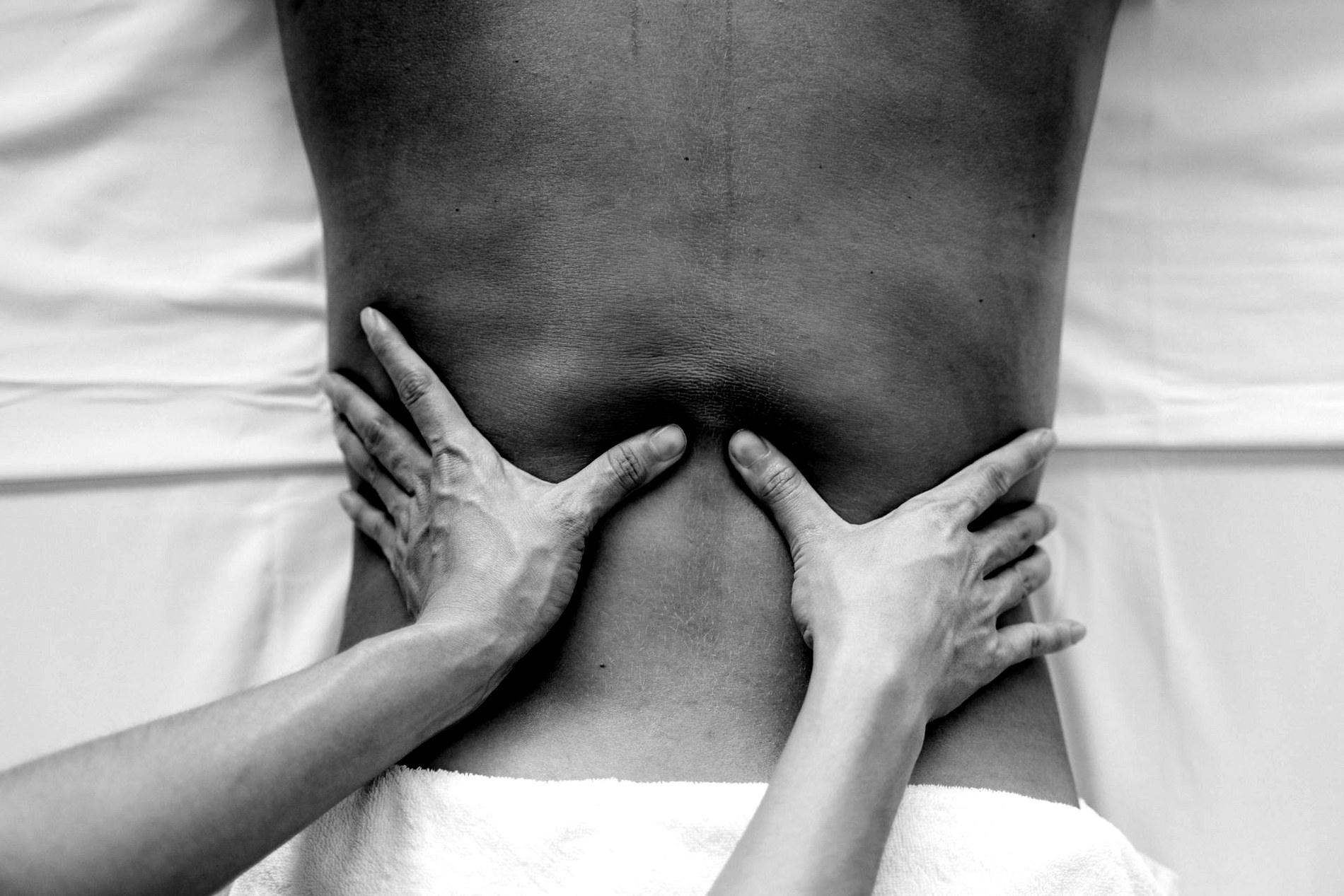 Black-and-white closeup of therapeutic massage work along the back.