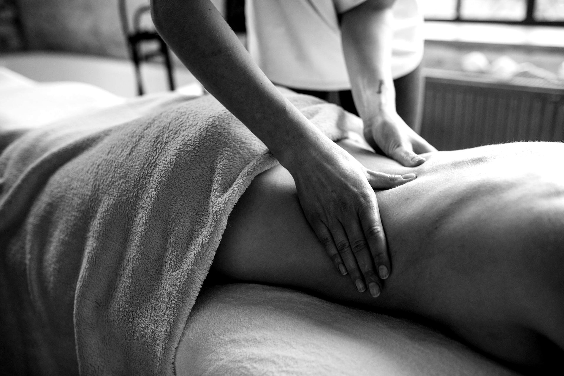 Black-and-white photo of a massage therapist applying steady pressure during a back massage.